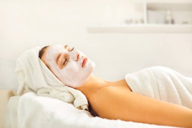 Spa salonunda bir kadının yüzünde kozmetik maske.
