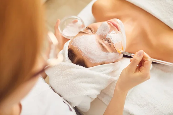 Gadis muda menerima masker wajah putih di salon kecantikan spa . — Stok Foto