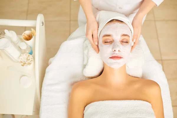 Kvinna i kosmetisk mask liggande i skönhetssalongen. — Stockfoto
