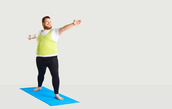 Gordo divertido hombre haciendo yoga sobre un fondo gris —  Fotos de Stock