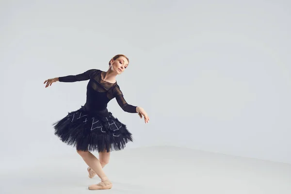 Ballerina in schwarzem Tutu tanzt elegant auf schwarzem Hintergrund. — Stockfoto