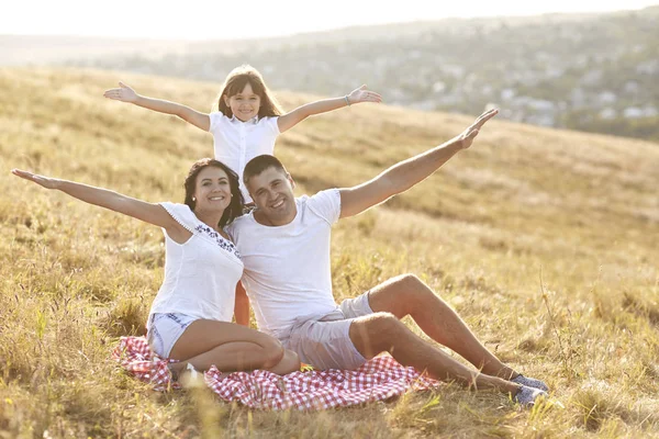 Щаслива сім'я сидить на траві на природі влітку . — стокове фото