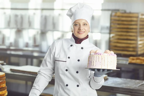 Konditor med konditori kaka i handen på bageriet. — Stockfoto