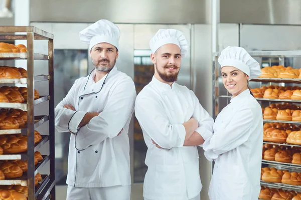 Padeiros no fundo de bandejas com pães em uma padaria . — Fotografia de Stock