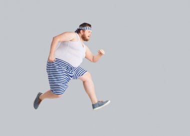 Funny man in striped shorts runs on a gray background. clipart