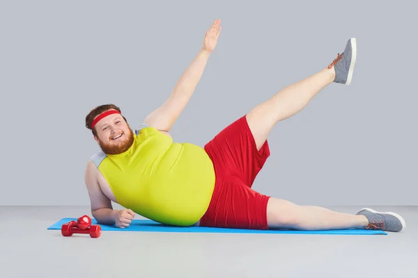 Fat funny man with a beard doing exercises goes in for sports.