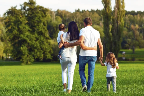 Arka görüş. Parkta yürüyen çocuklu mutlu aile. — Stok fotoğraf