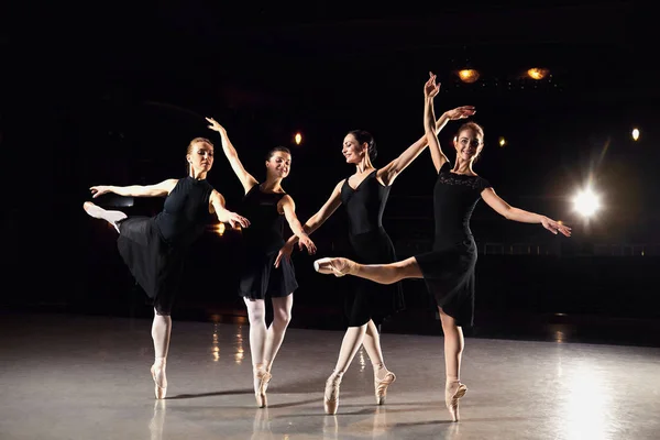 Um grupo de bailarinas está dançando na cena contra um fundo preto . — Fotografia de Stock