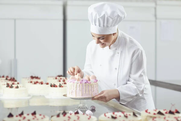 La pastelera sostiene un pastel en su mano en la panadería. . — Foto de Stock