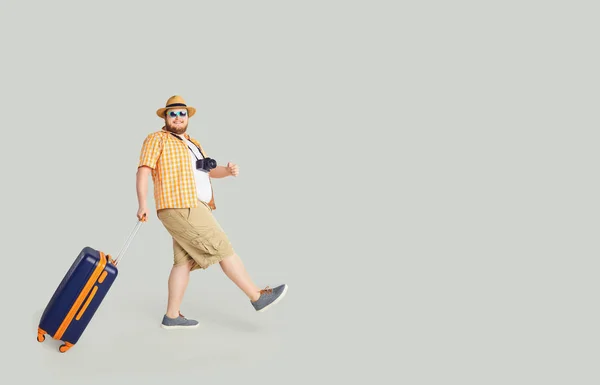 Rolig fet man med en resväska går att resa i grå bakgrund. — Stockfoto