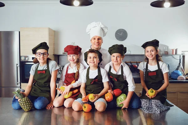Chef e crianças com legumes na cozinha elegante — Fotografia de Stock