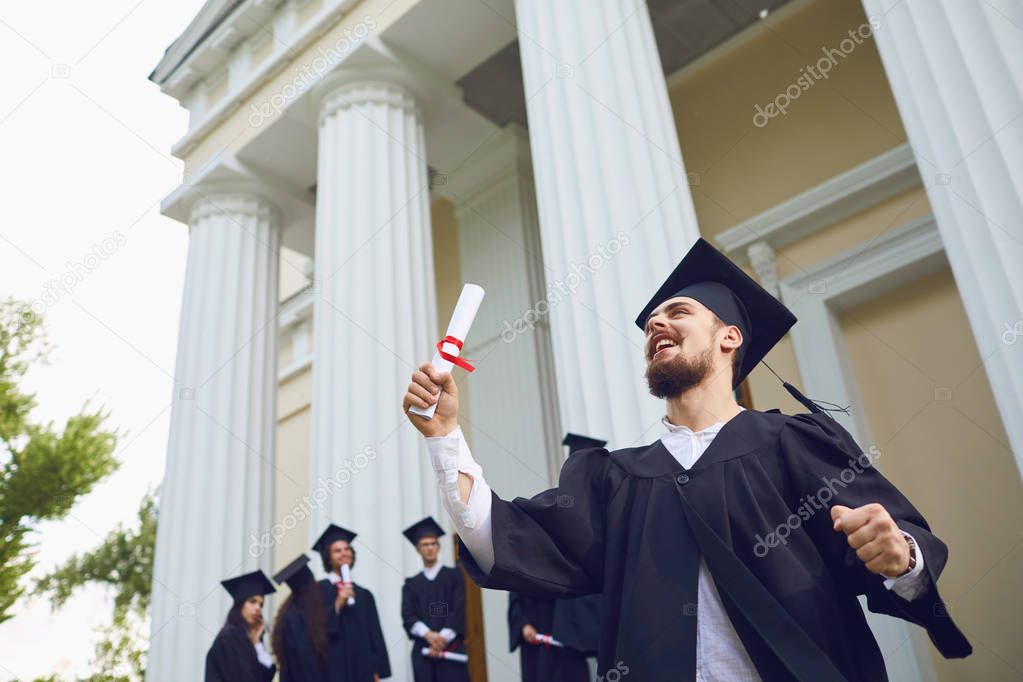 The guy with the scroll is smiling against the background of university graduates.
