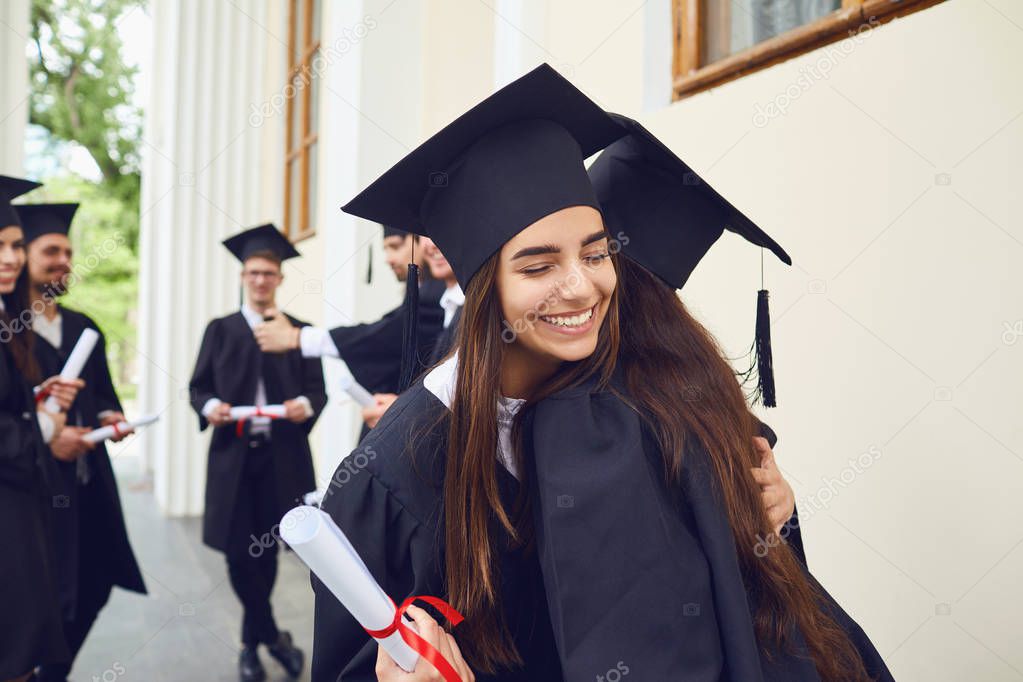 Female graduates with diplomas in their hands hugging