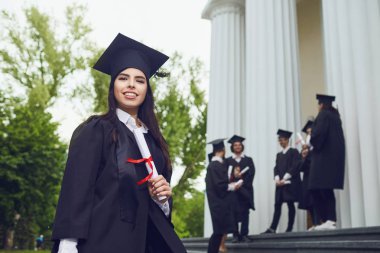 A girl graduate against the background of university graduates. clipart