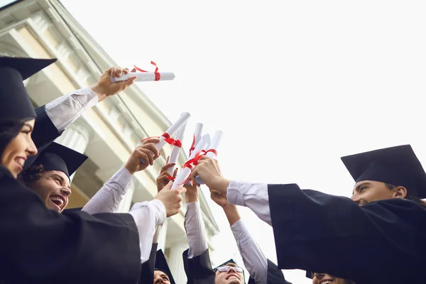 Scrolls diplomas in the hands of graduates. — Stock Photo, Image