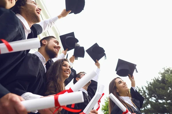 Šťastní absolventi zvedli ruce se svitky diplomů — Stock fotografie