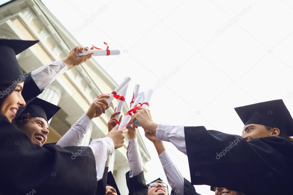 Scrolls diplomas in the hands of graduates.