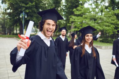 Man graduate is smiling against the background of university graduates. clipart