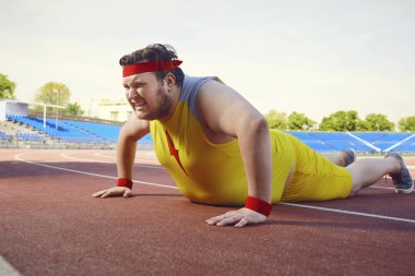 Spor kıyafetler giyen şişman bir adam şınav egzersizleri yapar.