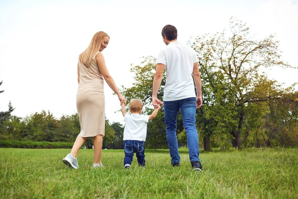 Rückseite. Familie mit Kind spaziert im Park. — Stockfoto