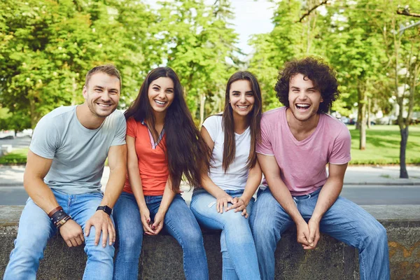 Un gruppo di giovani felici ride seduti in un parco . — Foto Stock