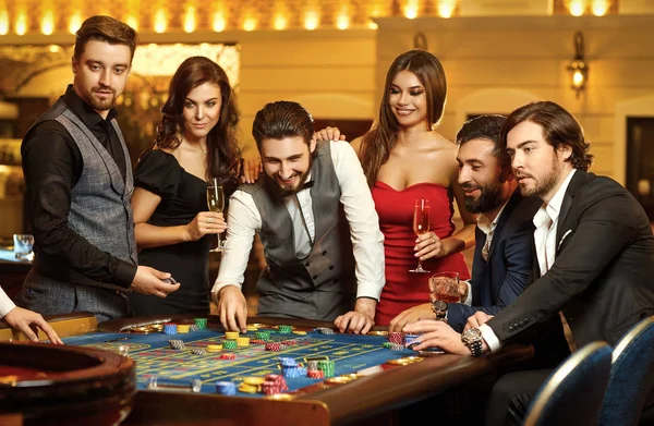 Friends make bets gambiling at the roulette table in the casino. — Stock Photo, Image