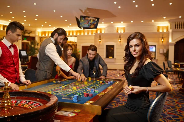 カジノでポーカーをしているテーブルルーレットに座っている若い女性. — ストック写真