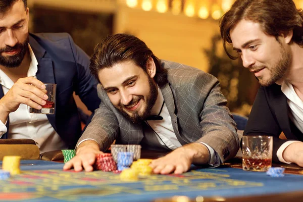 Hombre de grupo en un traje en la ruleta de mesa jugando póquer en un casino . —  Fotos de Stock