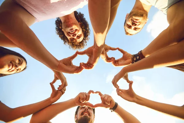 Handen van de groep mensen in de vorm van een hart tegen de hemel. — Stockfoto