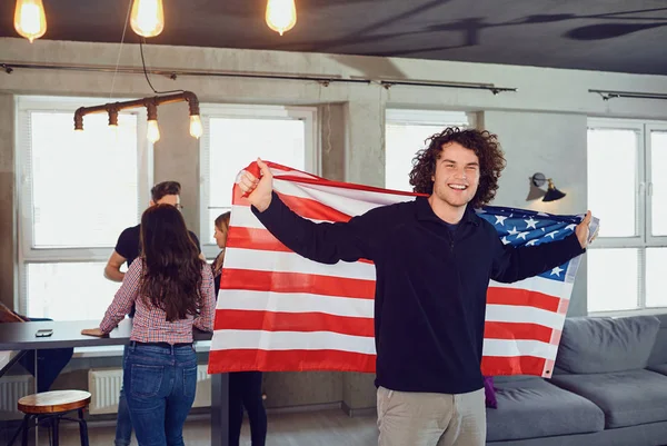 Man met een mooie glimlach met de vlag van Amerika binnenshuis. — Stockfoto