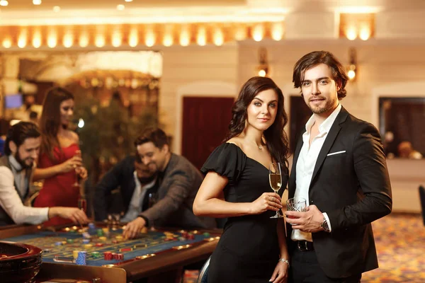 Schönes Glamour-Paar vor dem Hintergrund des Casino Poker Roulette. — Stockfoto