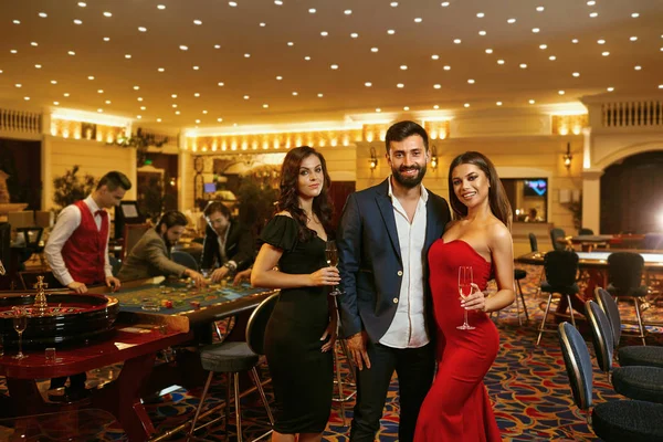Schöne Glamour Menschen lächeln gegen im Casino Poker Roulette. — Stockfoto