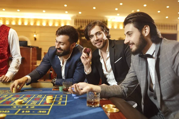 Jogador de grupo em um terno na roleta de mesa jogando poker em um cassino . — Fotografia de Stock