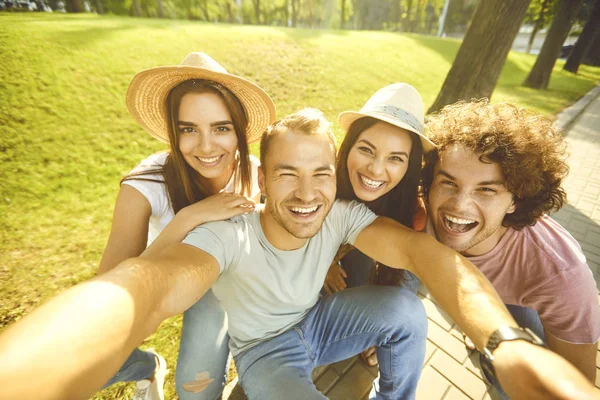 Jóvenes felices selfies fotos en el teléfono en el parque de la ciudad — Foto de Stock