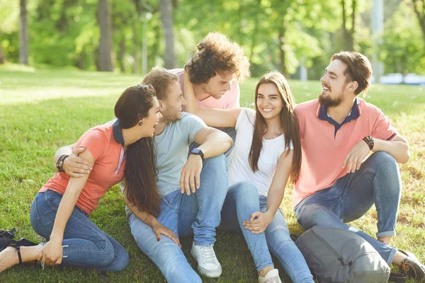 Amigos diversión sentado en la hierba en un parque de la ciudad —  Fotos de Stock