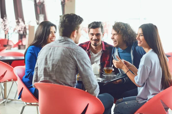 Komik arkadaşlar bir kafede bir masada oturan gülmek.