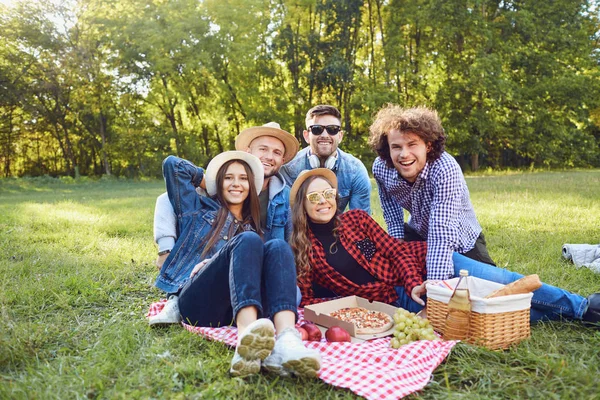 Un grupo de personas sentadas en la hierba en un picnic . — Foto de Stock