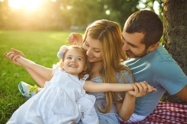 Parkta çimenlerin üzerinde oturan bebekli aile — Stok fotoğraf