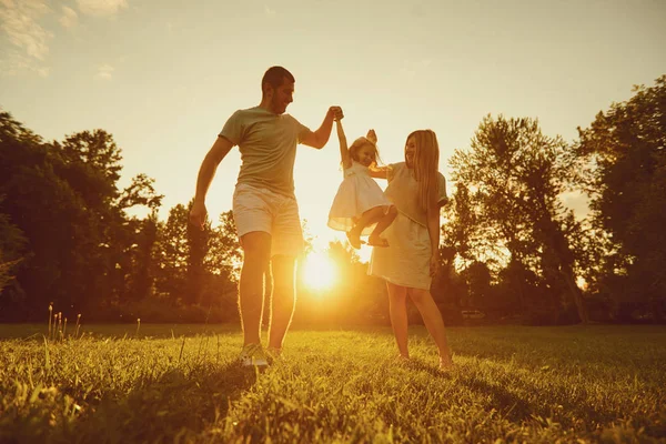 Familie spelen met een kind bij zonsondergang op de natuur — Stockfoto