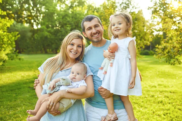 Bebekli bir aile parkta çimlerin üzerinde duruyor. — Stok fotoğraf