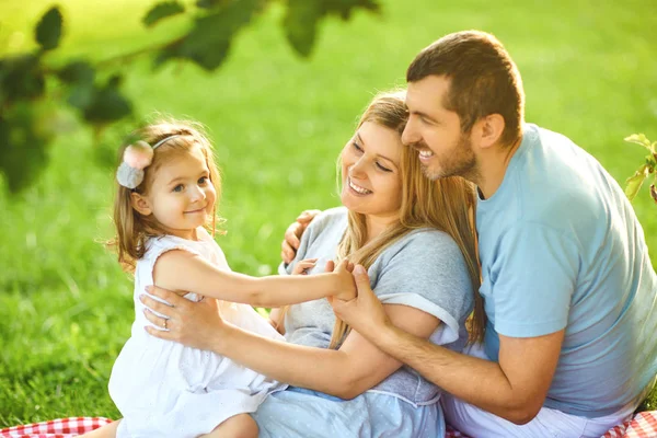 Parkta çimenlerin üzerinde oturan bebekli aile — Stok fotoğraf