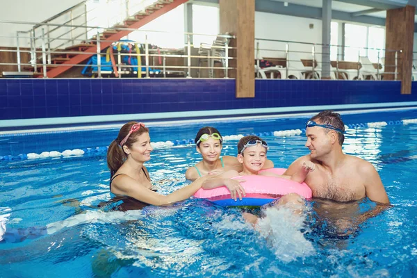 Μια ευτυχισμένη οικογένεια κολυμπά σε μια πισίνα σε εσωτερικούς χώρους. — Φωτογραφία Αρχείου