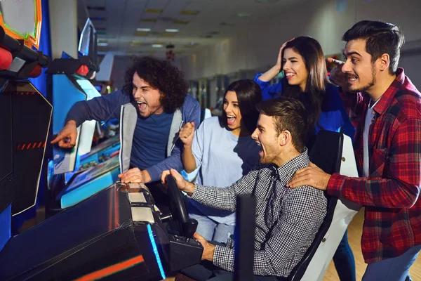 Un grupo de amigos jugando a la máquina arcade . —  Fotos de Stock