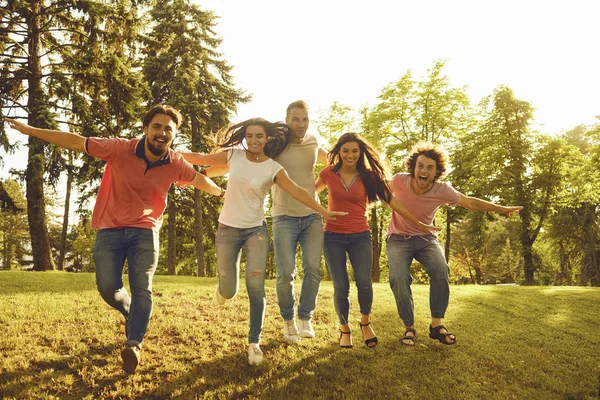 Vrienden plezier rennen op het gras in een stadspark — Stockfoto