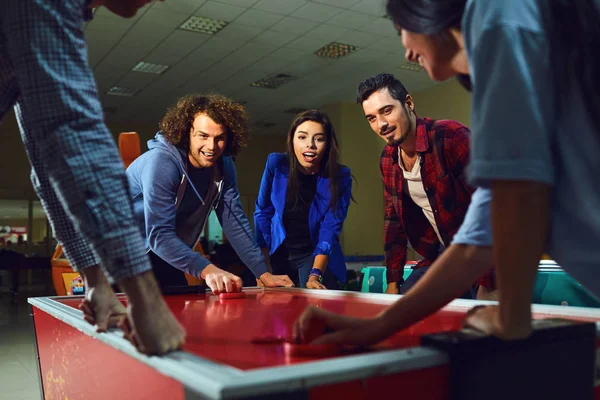 Een groep vrienden spelen Air Hockey in een pretpark. — Stockfoto