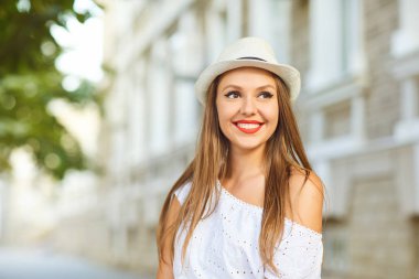 Bir şehir caddesinde beyaz giysiler ve şapka ile güzel kız.