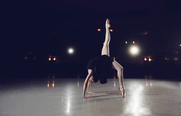 Bailarina em um terno preto está pulando em um fundo preto . — Fotografia de Stock