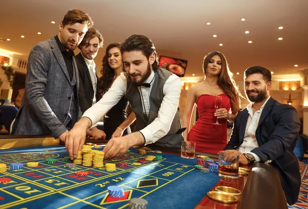 Un jeune homme avec des amis parie sur la roulette dans un casino . — Photo