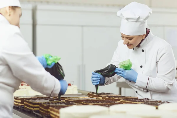 Un pastelero exprime crema líquida de una bolsa de pastelería . — Foto de Stock