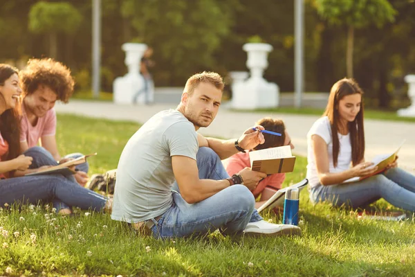 A group of students studying books sitting in a city park. — Stock Photo, Image